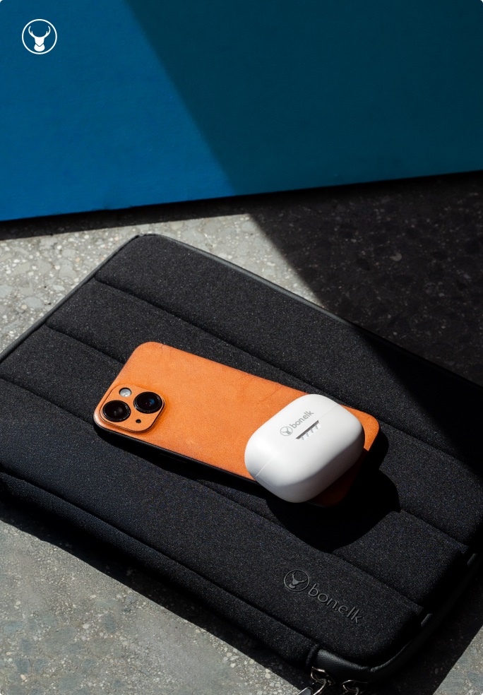 Bonelk phone case and earbuds on a padded laptop sleeve
