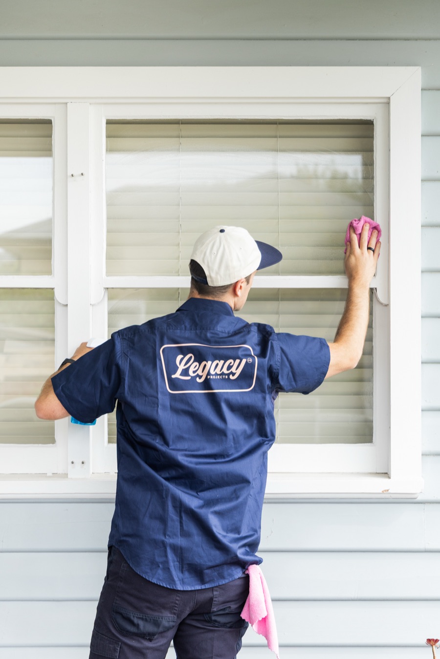 Legacy Co worker in branded shirt cleaning a window