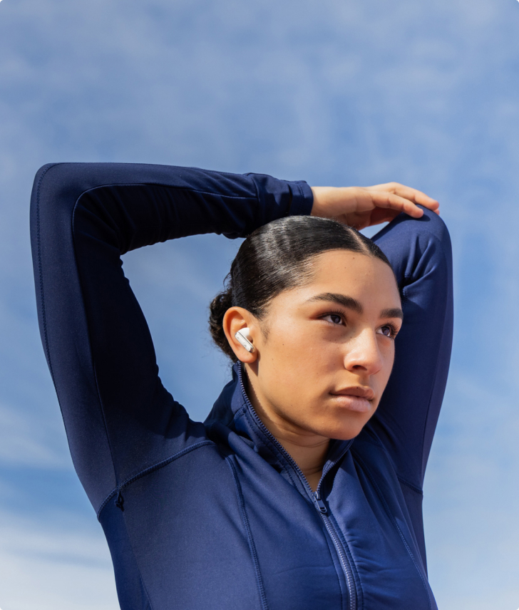 Woman in dark activewear stretching while wearing Bonelk wireless earbuds