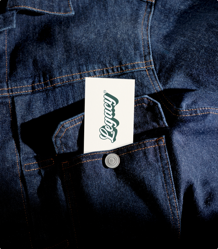 Cream Legacy business card tucked into the chest pocket of a dark denim work jacket