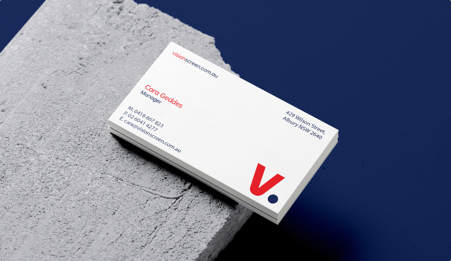 Vision Screenprinting business cards stacked on a concrete block against a navy background